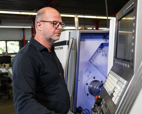 Mann steht vor einer Maschine mit einem großen Bildschirm